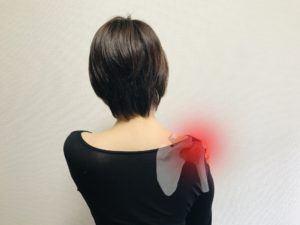 五十肩の痛みで右肩を押さえる女性
