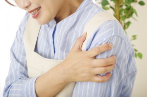 五十肩で腕が上がらず肩の付け根の痛みを訴える女性